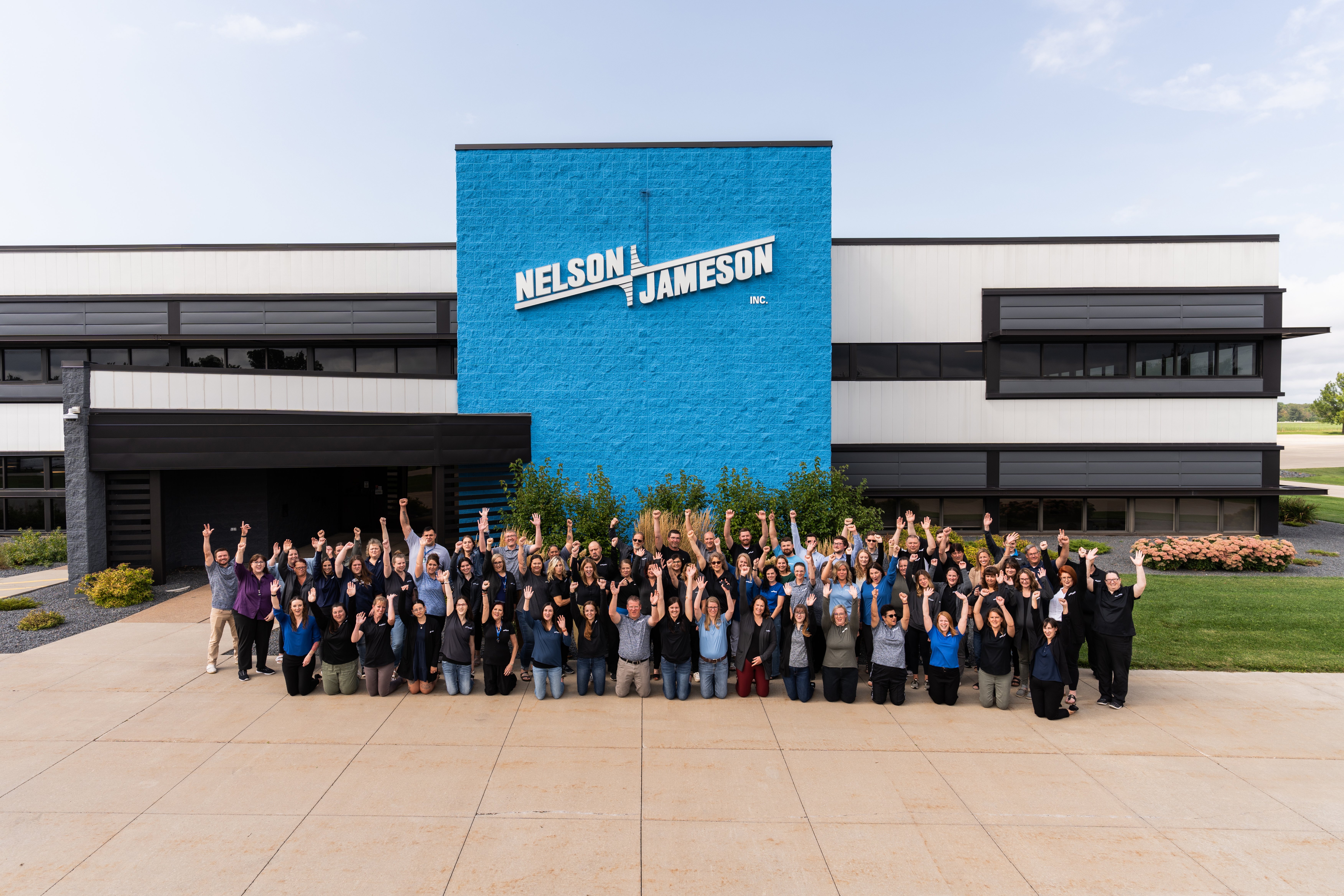 Employees-front-of-building-hands-in-air